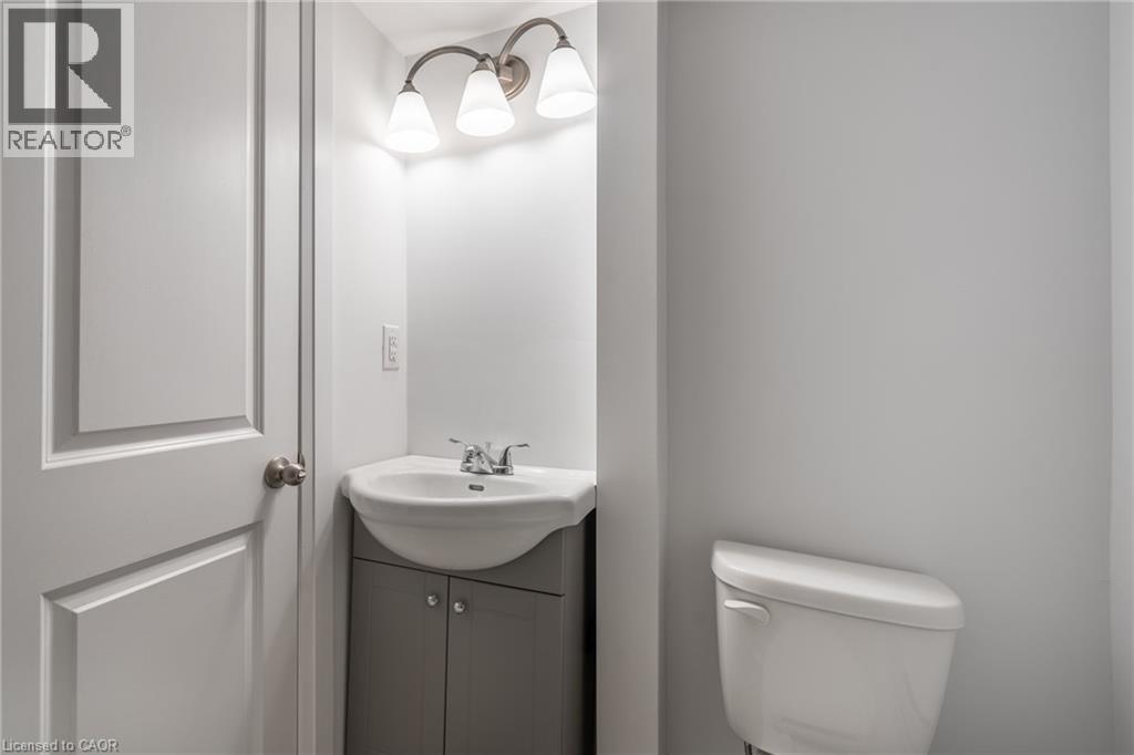 Powder room featuring a corner vanity with a white ceramic sink, brushed nickel faucet, and a three-light vanity fixture - 524 King Street E Unit# 3, Hamilton, ON - Indoor Photo Showing Bathroom