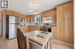 Kitchen featuring light wood-finish cabinetry, stainless steel appliances, a window above the sink, and light wood-finish flooring -