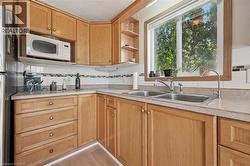 Kitchen featuring light wood-finish cabinetry, a double basin stainless steel sink, and light-toned countertops -