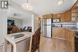 Kitchen featuring wood-finish flooring, oak cabinetry, stainless steel refrigerator, and built-in microwave -
