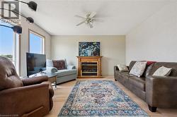 Living area featuring light wood-finish flooring, a built-in fireplace with a wood mantle, and a ceiling fan -