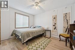 Spacious room featuring light wood-finish flooring, a large window with blinds, and a ceiling fan with integrated lighting -