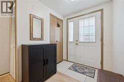 Entryway featuring a white door with transom window, white tile flooring, and a louvered closet door -