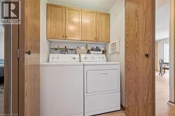 Dedicated laundry area featuring overhead cabinetry, a wood-finish shelf, and a light wood-finish floor -