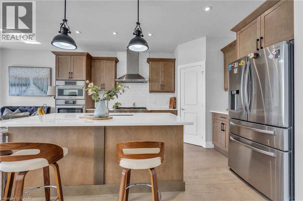 Kitchen featuring light wood-finish cabinetry, stainless steel appliances, a white subway tile backsplash, and a large island with a light-toned countertop - 2195 Ironwood Road, London, ON - Indoor Photo Showing Kitchen With Stainless Steel Kitchen With Upgraded Kitchen