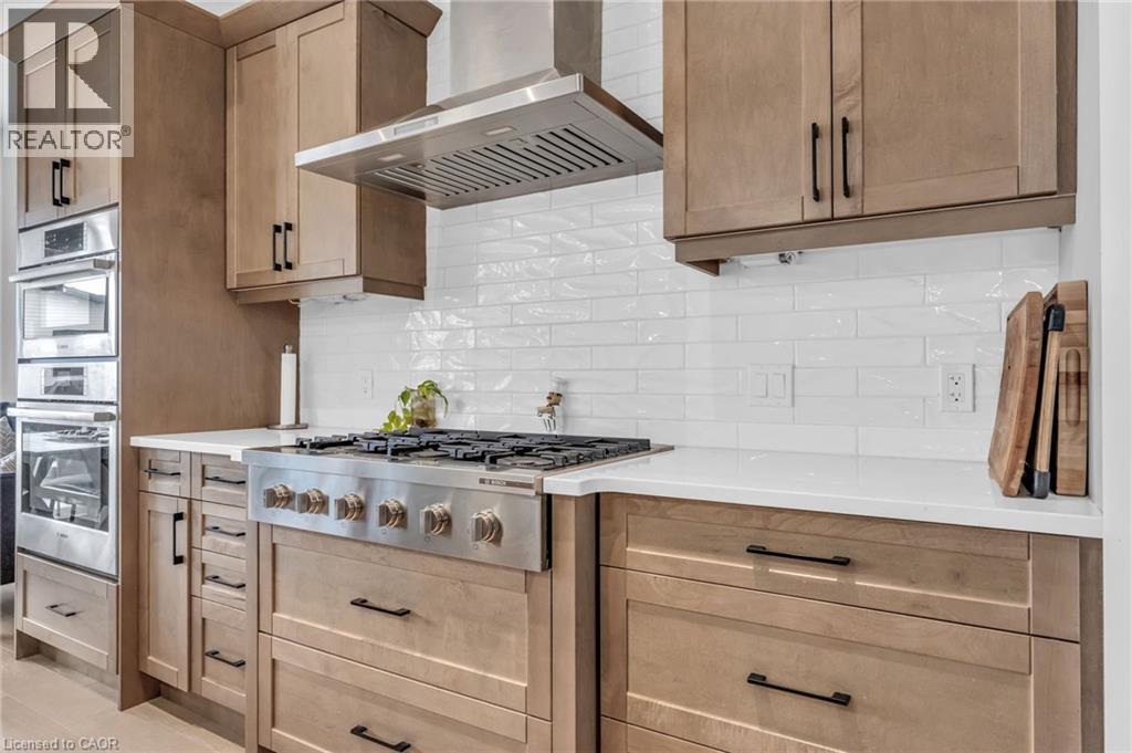 Stainless steel range with a coordinating hood, surrounded by light wood-finish cabinetry - 2195 Ironwood Road, London, ON - Indoor Photo Showing Kitchen With Upgraded Kitchen