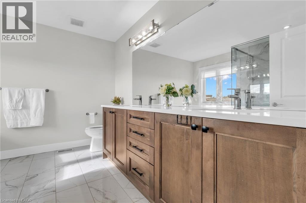 Bathroom featuring a dual vanity with wood cabinetry, white countertops, and chrome fixtures - 2195 Ironwood Road, London, ON - Indoor Photo Showing Bathroom
