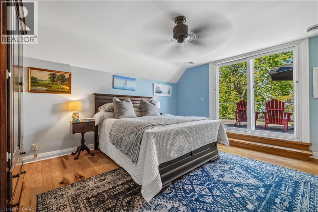 Bedroom featuring hardwood flooring, a ceiling fan, a built-in wardrobe, and sliding glass doors opening to an exterior deck - 573 Beach Boulevard, Hamilton, ON - Indoor Photo Showing Bedroom