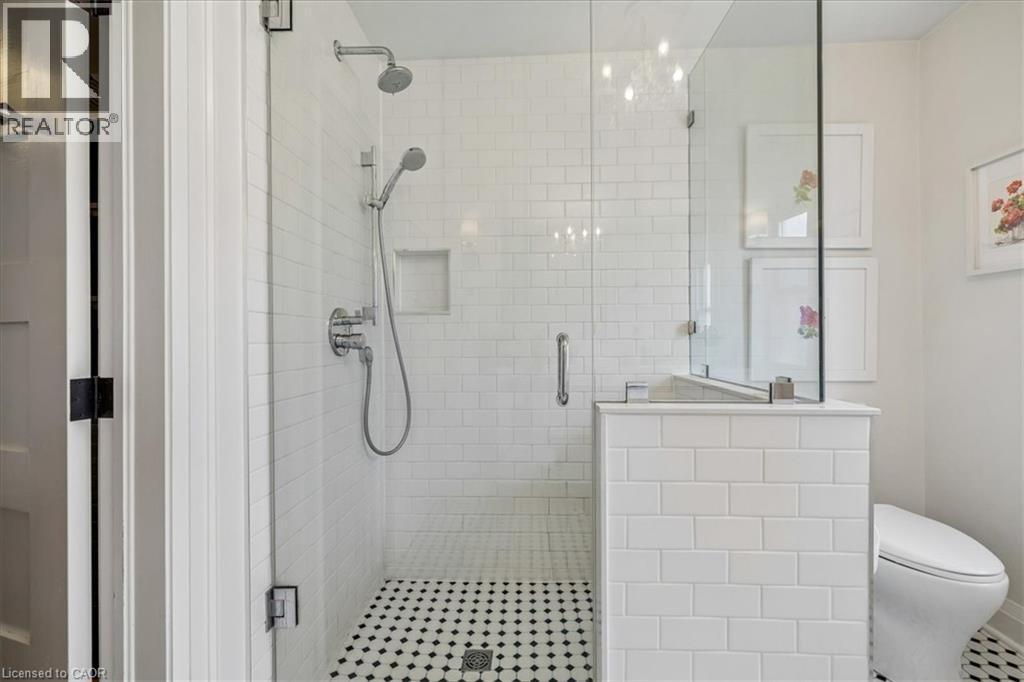 Glass-enclosed shower featuring white subway tile walls and a black-and-white hex tile floor - 573 Beach Boulevard, Hamilton, ON - Indoor Photo Showing Bathroom