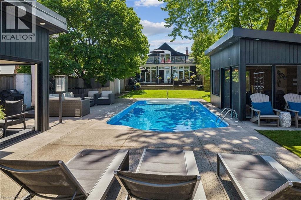 Expansive backyard featuring a rectangular swimming pool with integrated spa, concrete patio, and manicured lawn - 573 Beach Boulevard, Hamilton, ON - Outdoor With In Ground Pool With Deck Patio Veranda