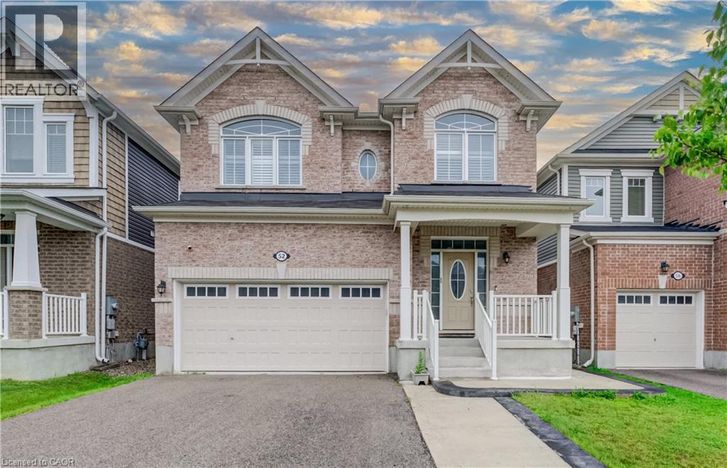 Brick-clad exterior featuring a covered porch with white railings, a two-car garage, and an arched window - 52 Pointer Street, Cambridge, ON - Outdoor With Facade