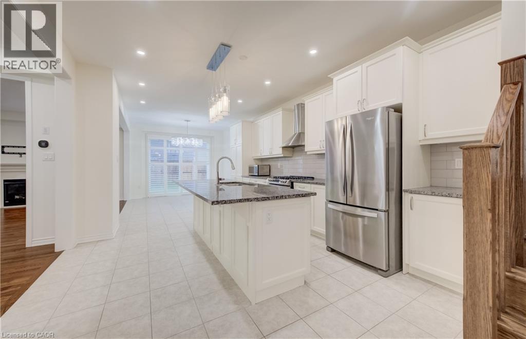 Spacious kitchen featuring an island with a built-in sink, white cabinetry, stainless steel appliances, granite countertops, and tile flooring - 52 Pointer Street, Cambridge, ON - Indoor Photo Showing Kitchen With Upgraded Kitchen