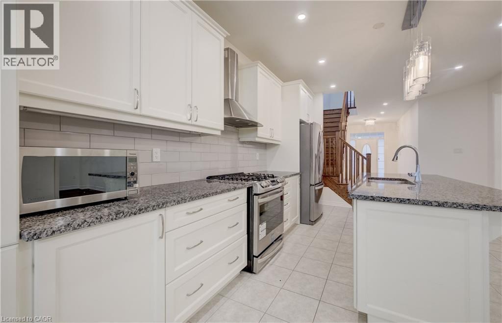 Kitchen featuring white shaker-style cabinetry, granite countertops, subway tile backsplash, stainless steel appliances, and tile flooring - 52 Pointer Street, Cambridge, ON - Indoor Photo Showing Kitchen With Upgraded Kitchen