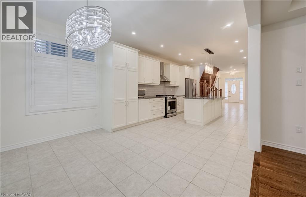 Spacious kitchen featuring white cabinetry, stainless steel appliances, a center island with sink, and tile flooring - 52 Pointer Street, Cambridge, ON - Indoor Photo Showing Kitchen