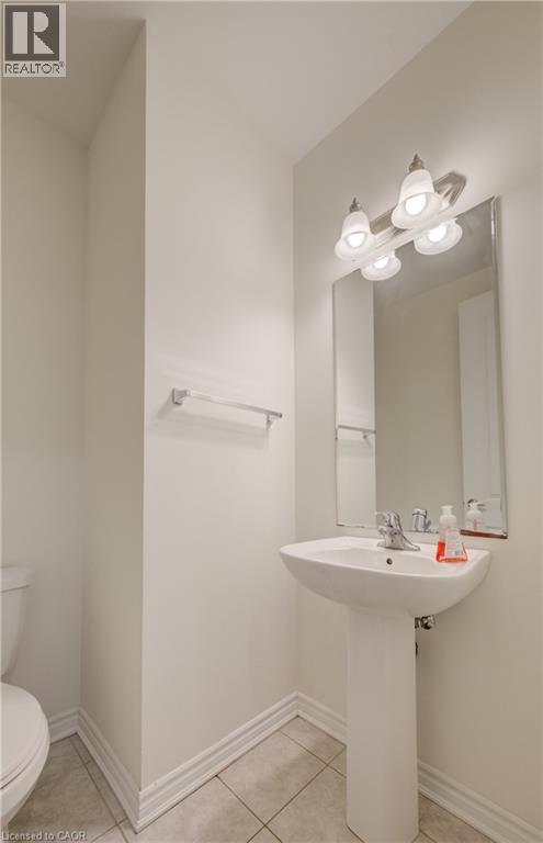Pedestal sink with chrome faucet, complemented by a rectangular wall mirror and a three-light vanity fixture - 52 Pointer Street, Cambridge, ON - Indoor Photo Showing Bathroom
