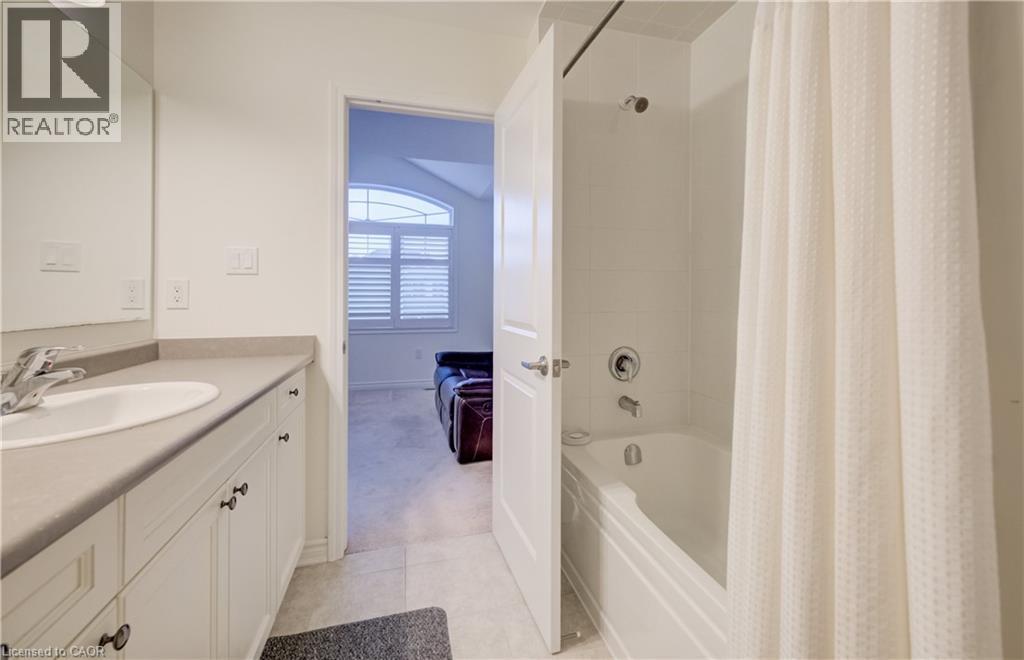 Bathroom featuring a white vanity with an integrated sink and light-toned countertop, a full-width mirror, and a shower-over-tub combination with white subway tile surround - 52 Pointer Street, Cambridge, ON - Indoor Photo Showing Bathroom