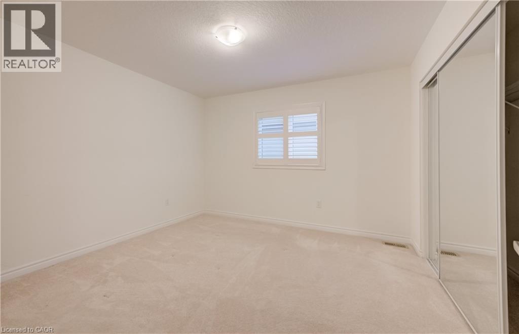 Spacious room with plush carpet, a window featuring white plantation shutters, and a wall-length mirrored closet - 52 Pointer Street, Cambridge, ON - Indoor Photo Showing Other Room
