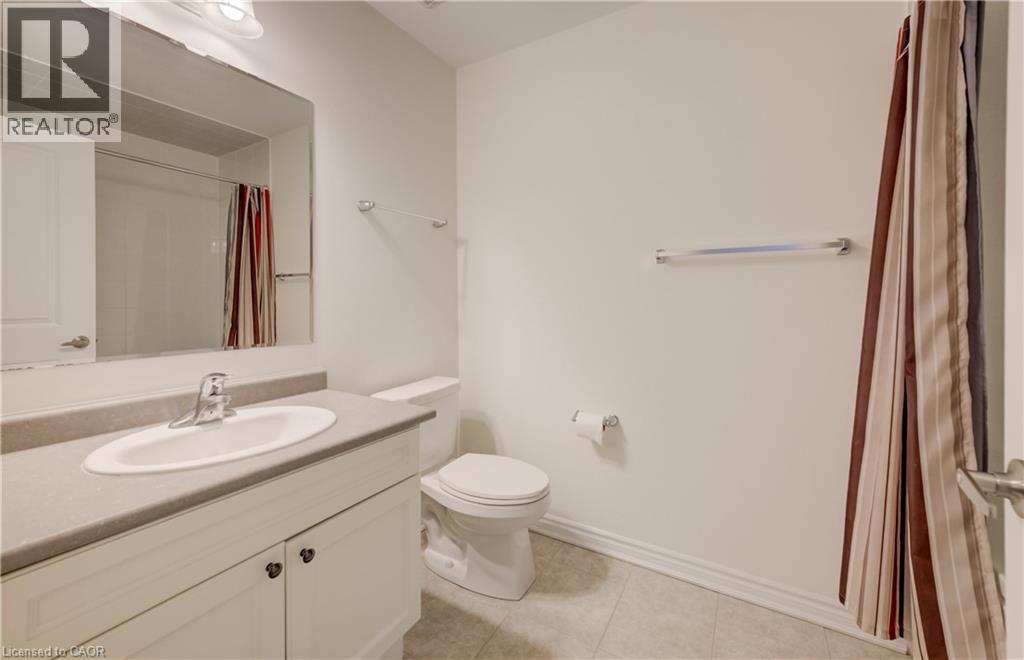 Bathroom featuring a white vanity with an integrated sink, a neutral countertop, a large wall-mounted mirror, and tile flooring - 52 Pointer Street, Cambridge, ON - Indoor Photo Showing Bathroom