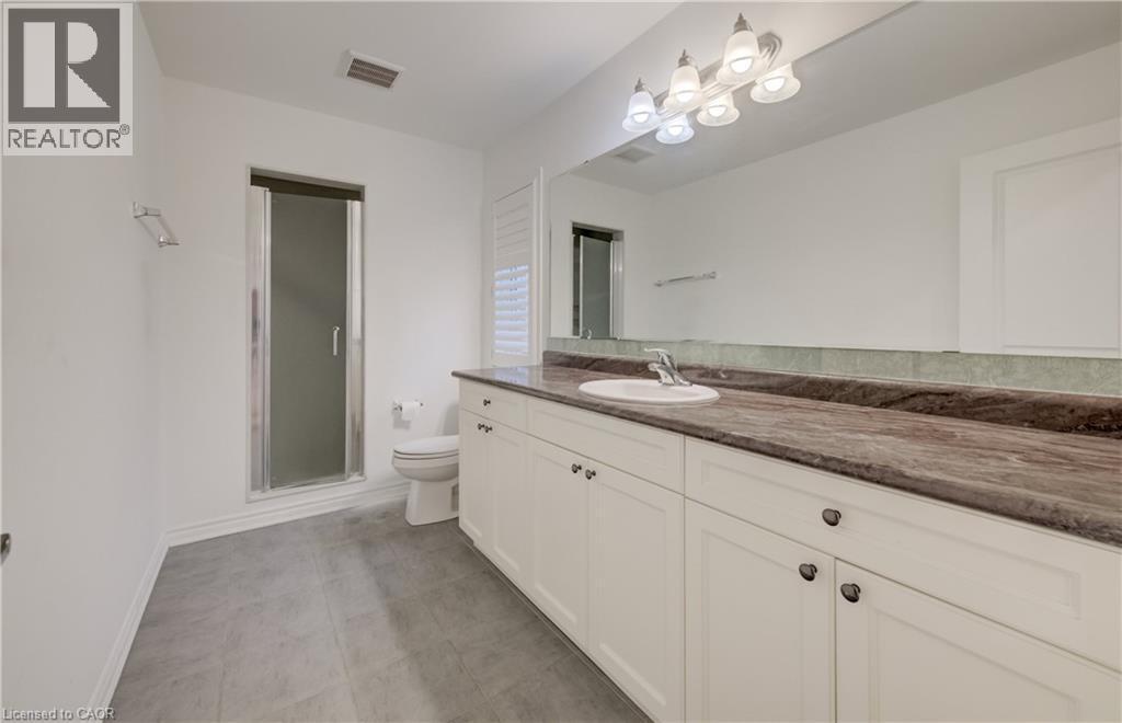 Bathroom featuring a long vanity with dual under-mount sinks, a dark stone countertop, and extensive white cabinetry - 52 Pointer Street, Cambridge, ON - Indoor Photo Showing Bathroom