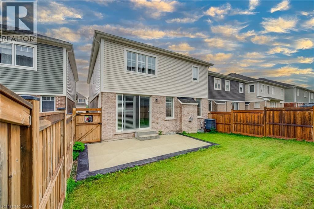 Rear exterior featuring a concrete patio, sliding glass door entry, and a spacious grass lawn - 52 Pointer Street, Cambridge, ON - Outdoor