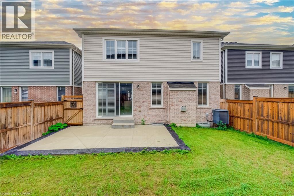 Rear exterior featuring a ground-level patio, a grass lawn, and wood fencing - 52 Pointer Street, Cambridge, ON - Outdoor