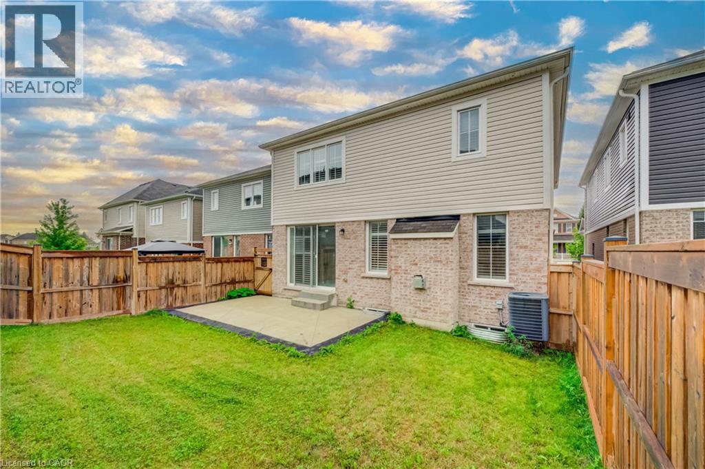 Spacious backyard featuring a concrete patio, a sliding glass door, and wood privacy fencing - 52 Pointer Street, Cambridge, ON - Outdoor