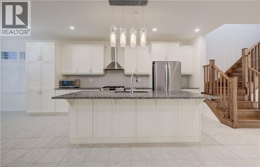 Kitchen featuring a central island with a sink, white cabinetry, integrated stainless steel appliances, and tile flooring - 52 Pointer Street, Cambridge, ON - Indoor Photo Showing Kitchen With Upgraded Kitchen