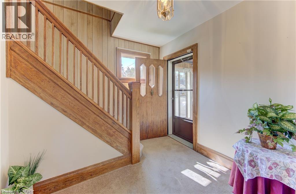 Inviting entry area featuring a detailed wood staircase, a solid wood entry door with decorative glass, and a large window providing ambient light - 224 Weber Street E, Kitchener, ON - Indoor Photo Showing Other Room