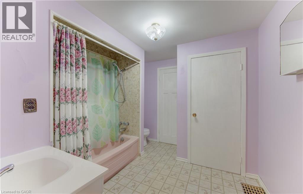 Main floor Bathroom featuring a built-in tub with an integrated shower, vanity with an undermount sink, and patterned flooring - 224 Weber Street E, Kitchener, ON - Indoor Photo Showing Bathroom