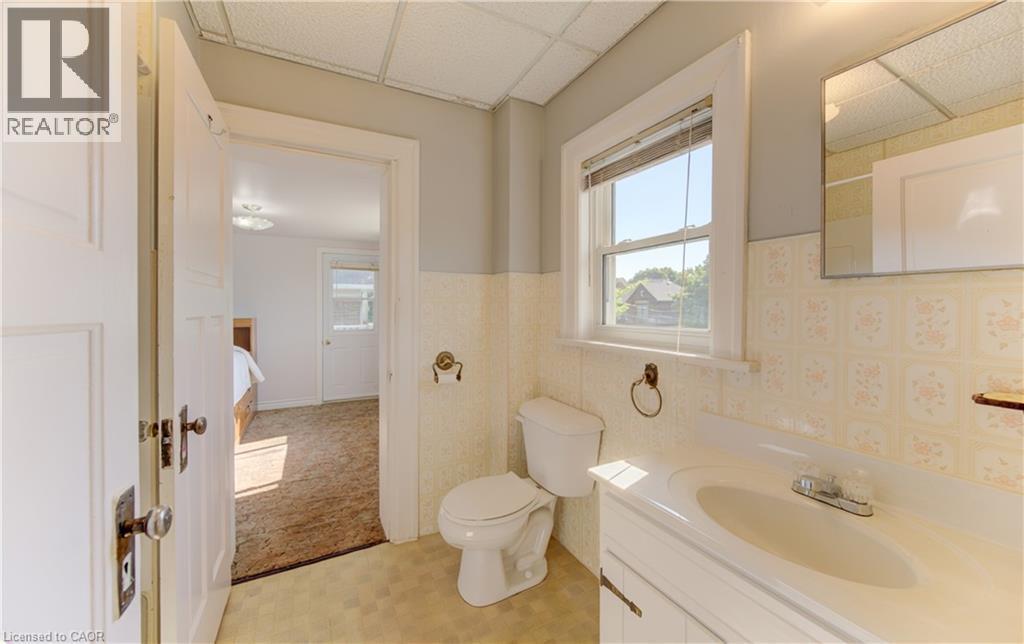 Bathroom featuring a single window, a white vanity with an integrated sink, a toilet, patterned wall tile, and a mirrored medicine cabinet - 224 Weber Street E, Kitchener, ON - Indoor Photo Showing Bathroom