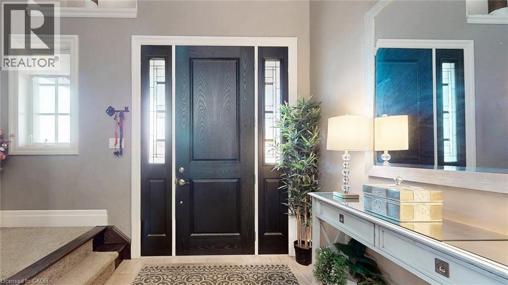 Entryway featuring a dark wood-finish door with sidelights, a framed mirror, and a console table with a glass top - 537 Millstream Drive, Waterloo, ON - Indoor Photo Showing Other Room