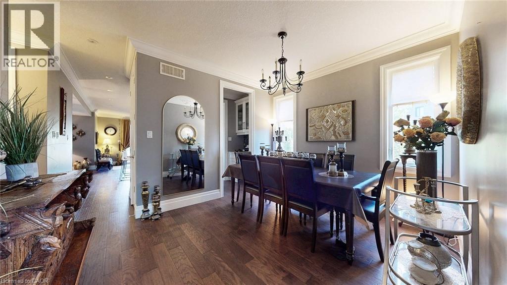 Expansive dining area featuring wood-finish flooring, a chandelier light fixture, crown molding, and two large windows - 537 Millstream Drive, Waterloo, ON - Indoor Photo Showing Dining Room