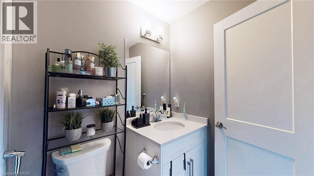 Bathroom featuring a white vanity with an integrated sink, a wall-mounted mirror, and a contemporary light fixture - 537 Millstream Drive, Waterloo, ON - Indoor Photo Showing Bathroom