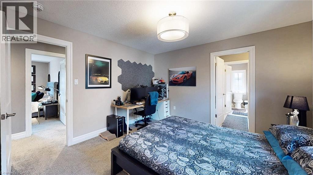 Neutral-toned walls and carpeted flooring define this room, featuring a contemporary drum pendant light fixture - 537 Millstream Drive, Waterloo, ON - Indoor Photo Showing Bedroom