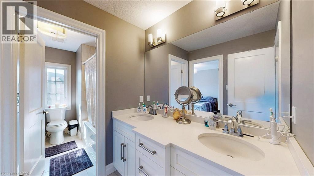 Bathroom featuring a dual vanity with white cabinetry, integrated sinks, and a light-toned countertop - 537 Millstream Drive, Waterloo, ON - Indoor Photo Showing Bathroom