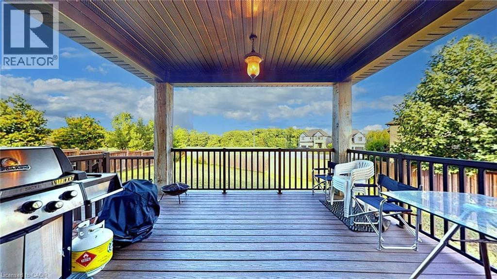Spacious covered deck featuring composite wood-finish flooring, dark railing, and a central overhead light fixture - 537 Millstream Drive, Waterloo, ON - Outdoor With Deck Patio Veranda With Exterior