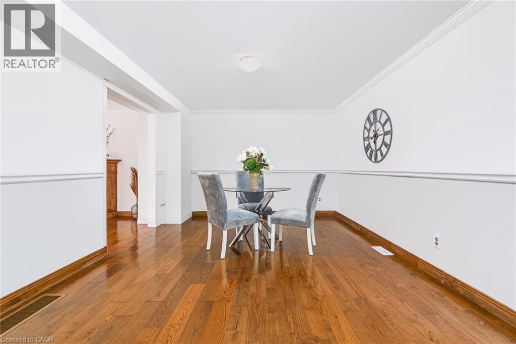 Spacious dining area featuring rich wood-finish flooring, crisp white walls with chair rail molding, and a seamless transition to an adjacent room - 34 Peachtree Crescent, Cambridge, ON - Indoor Photo Showing Dining Room