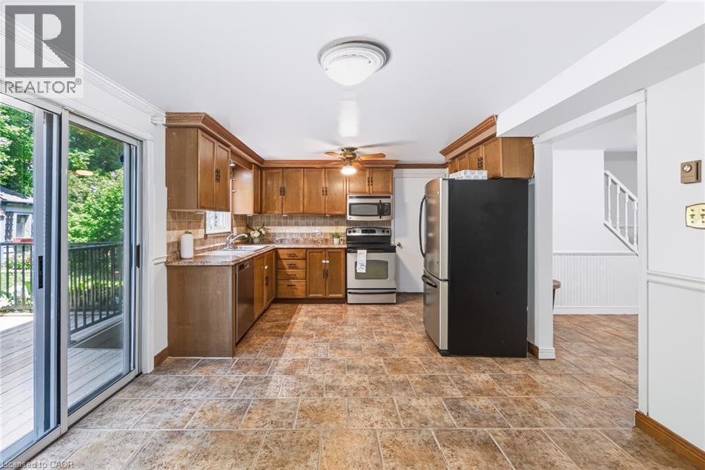 Kitchen featuring wood cabinetry, stainless steel appliances, tile flooring, and a sliding glass door to an outdoor deck - 34 Peachtree Crescent, Cambridge, ON - Indoor Photo Showing Kitchen