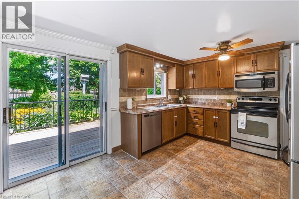 Kitchen with wood-finish cabinetry, stainless steel appliances, and a tiled backsplash - 34 Peachtree Crescent, Cambridge, ON - Indoor Photo Showing Kitchen