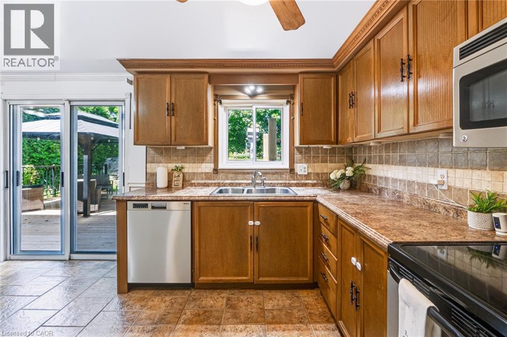 Kitchen featuring wood cabinetry, a stainless steel double basin sink, and a multi-toned tile backsplash - 34 Peachtree Crescent, Cambridge, ON - Indoor Photo Showing Kitchen With Double Sink