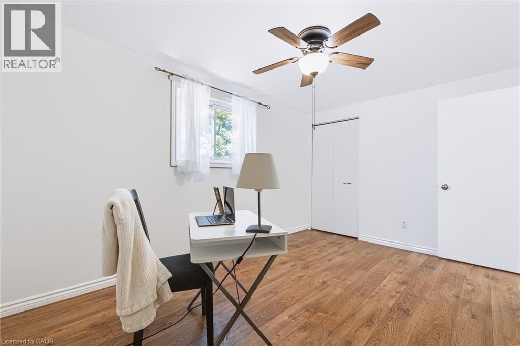 Bright room featuring wood-finish flooring, a window with white sheer curtains, a ceiling fan with integrated lighting, and white walls - 34 Peachtree Crescent, Cambridge, ON - Indoor