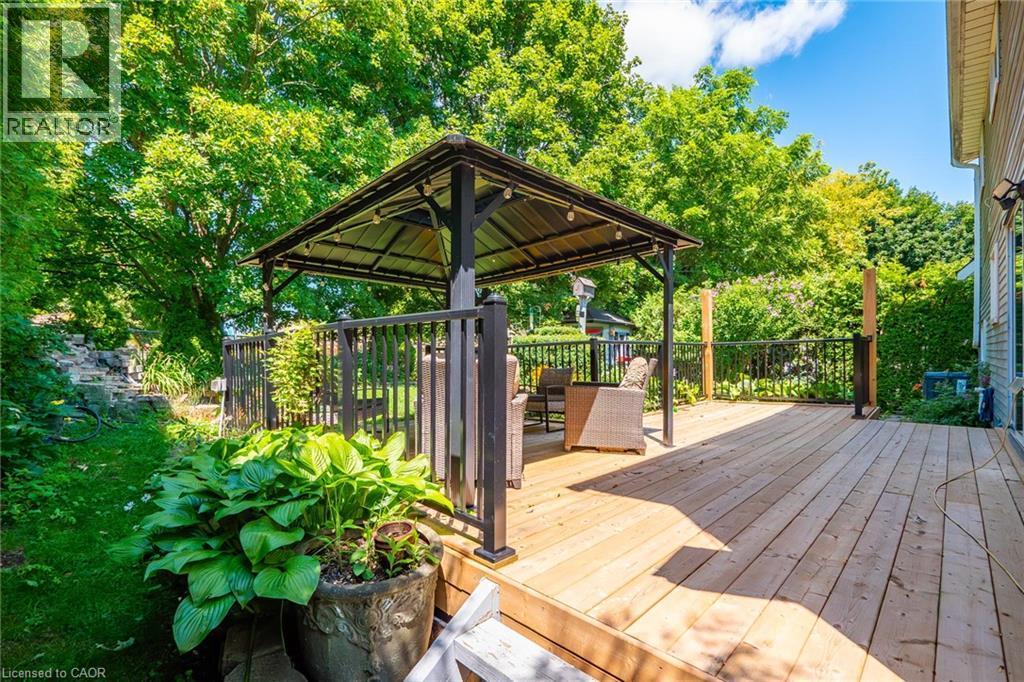 Expansive wood deck featuring a covered gazebo with string lighting, dark railings, and lush perimeter greenery - 34 Peachtree Crescent, Cambridge, ON - Outdoor With Deck Patio Veranda