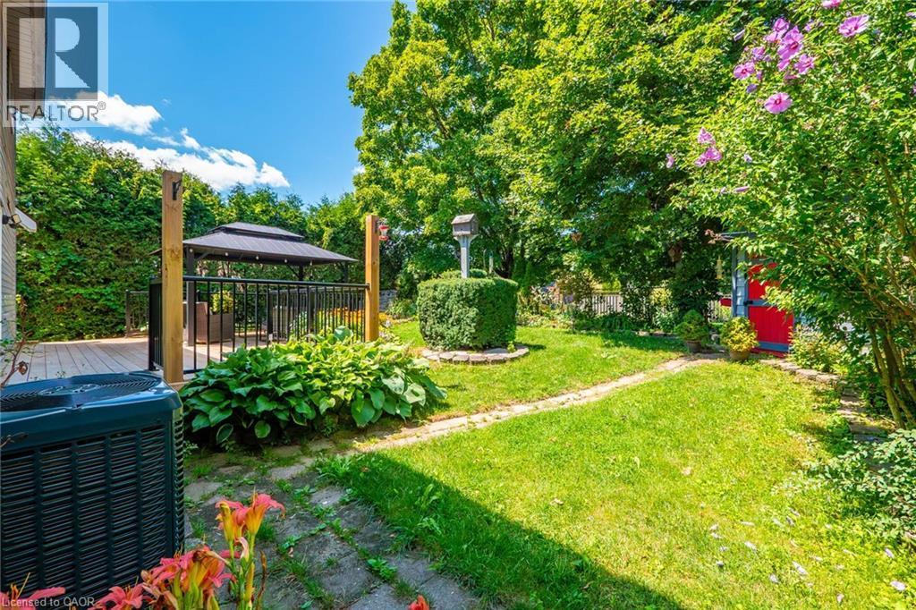 Outdoor living area featuring a wooden deck with a black metal railing, a covered gazebo, and lush perimeter greenery - 34 Peachtree Crescent, Cambridge, ON - Outdoor