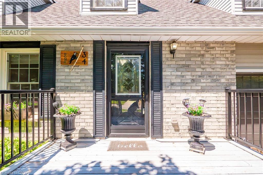 Front entry featuring a full light storm door with decorative glass, flanked by dark shutters and a light brick facade - 34 Peachtree Crescent, Cambridge, ON - Outdoor With Exterior