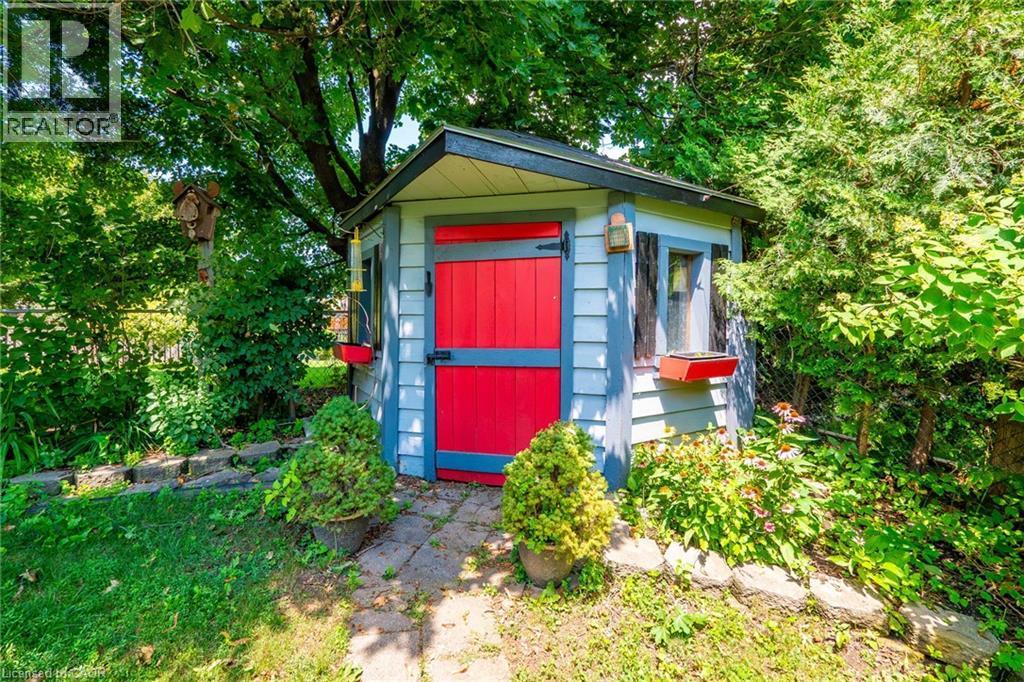 Garden shed featuring light blue siding with dark trim, a red Dutch door, and two small windows with flower boxes - 34 Peachtree Crescent, Cambridge, ON - Outdoor