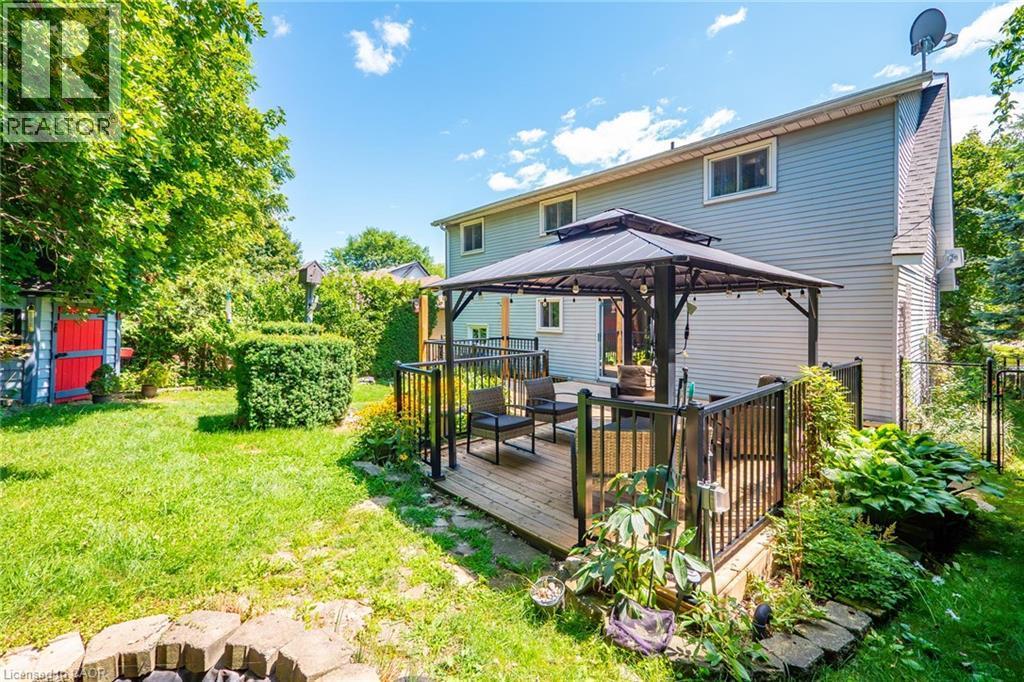 Rear exterior showcasing a wood-finish deck with a gazebo, surrounded by mature trees and manicured landscaping - 34 Peachtree Crescent, Cambridge, ON - Outdoor With Deck Patio Veranda