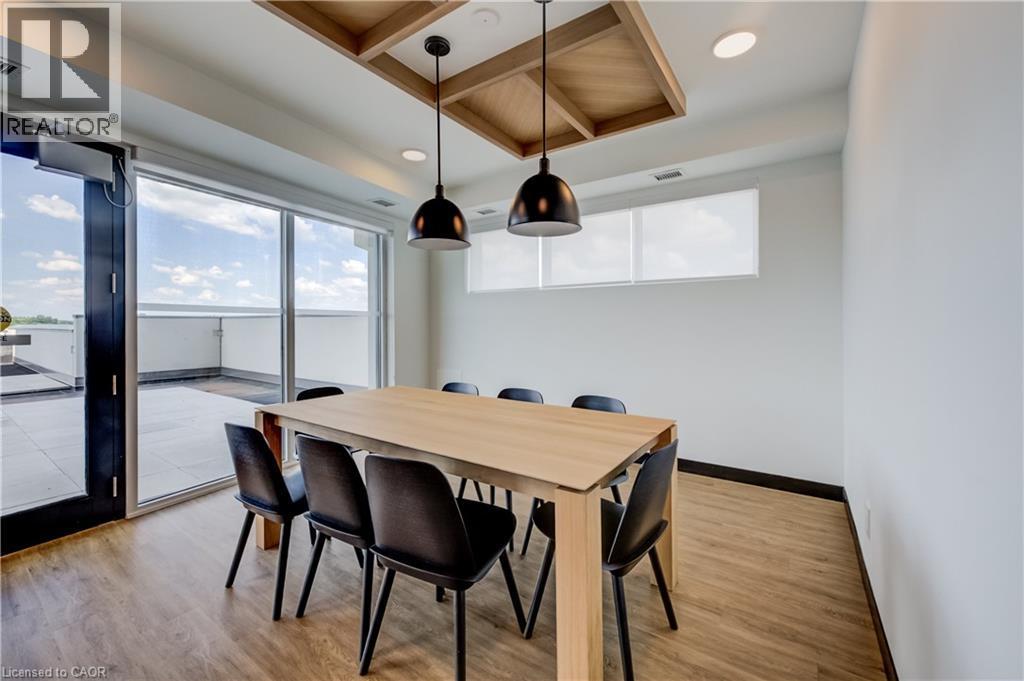 Dining space featuring wood-finish flooring, a large sliding glass door opening to a tiled balcony, recessed ceiling lights, and two pendant light fixtures - 1333 Weber Street E Unit# 708, Kitchener, ON - Indoor Photo Showing Dining Room
