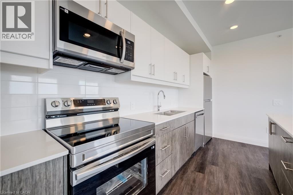 Contemporary kitchen featuring stainless steel appliances, white subway tile backsplash, and light-toned wood-finish lower cabinetry - 1333 Weber Street E Unit# 708, Kitchener, ON - Indoor Photo Showing Kitchen With Stainless Steel Kitchen With Upgraded Kitchen