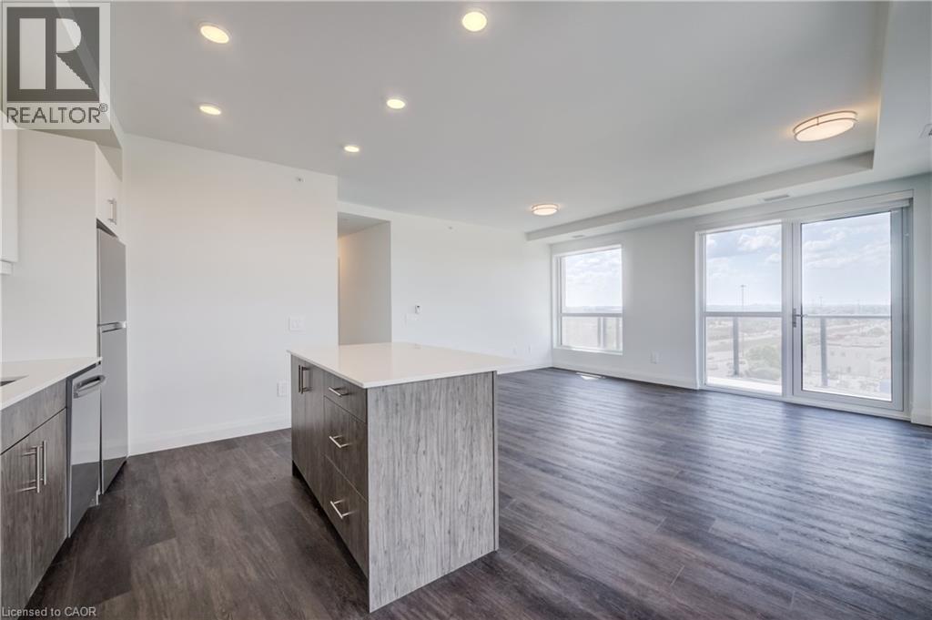 Open-concept living area with dark wood-finish flooring, white walls, and recessed ceiling lighting - 1333 Weber Street E Unit# 708, Kitchener, ON - Indoor Photo Showing Kitchen