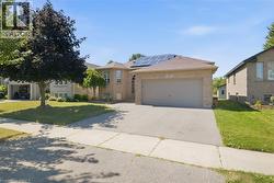 Brick exterior residence featuring a two-car garage, solar panels, and a paved driveway - 